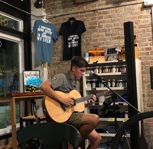 A young man playing an acoustic guitar in a store.