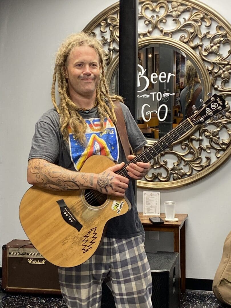 A Man With Blond Dreadlocks Holding a Guitar