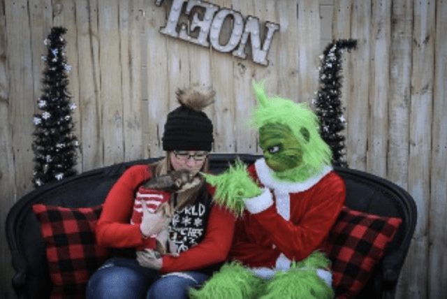 A woman sits on a couch next to a grinch.