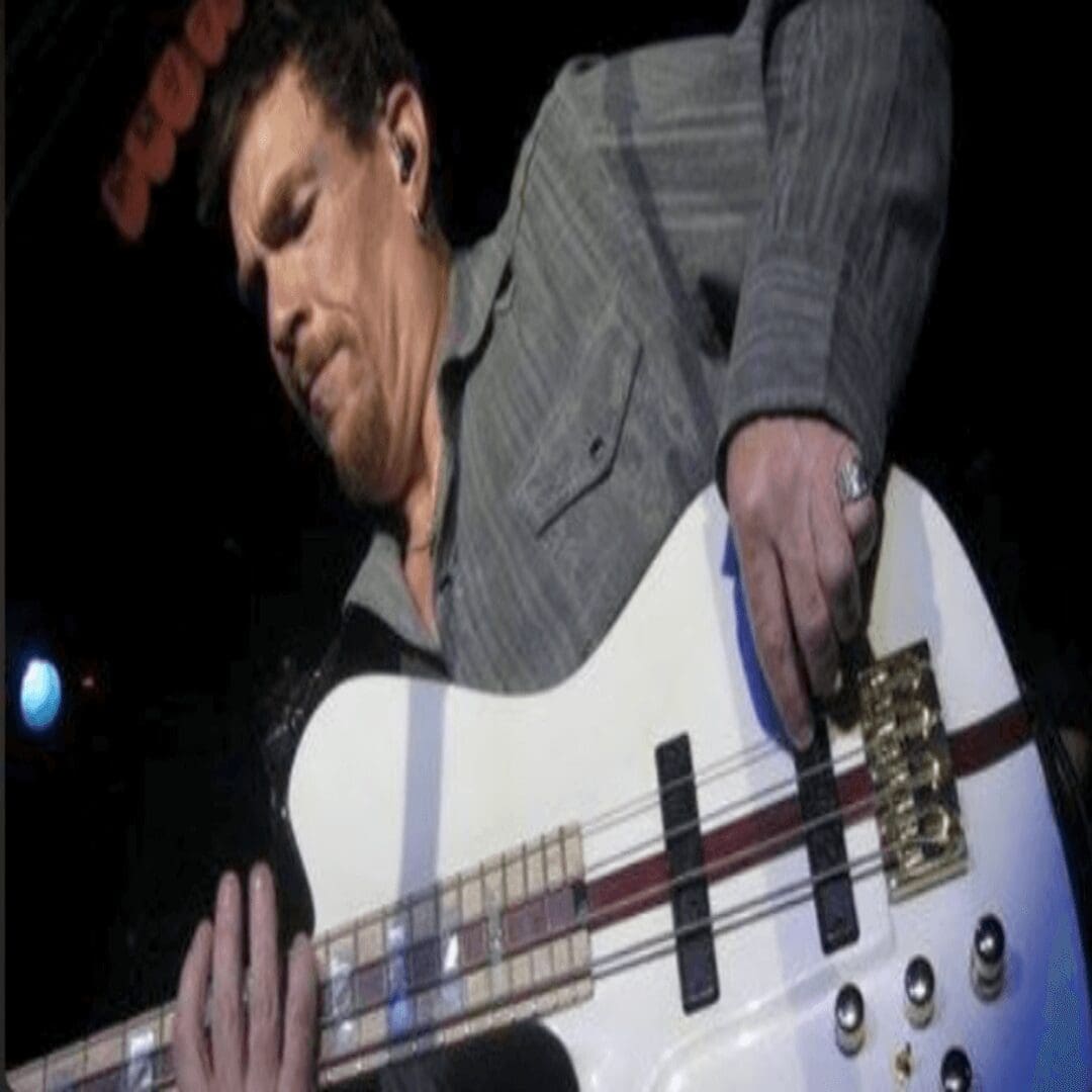 A man playing a white bass guitar.