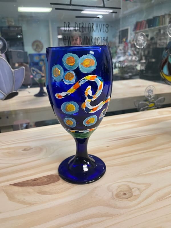 A blue wine glass with a colorful design on it.