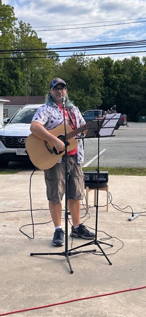 A man playing an acoustic guitar in a parking lot.