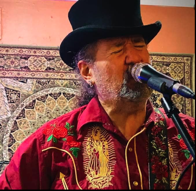 A man in a hat singing into a microphone.